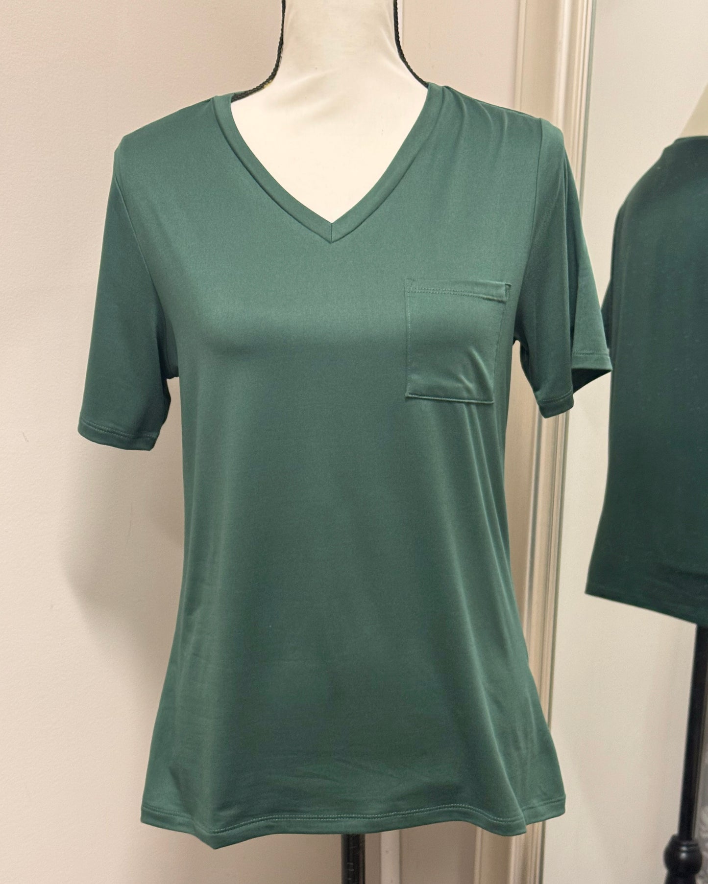 Green t-shirt with a pocket on a mannequin against a white wall