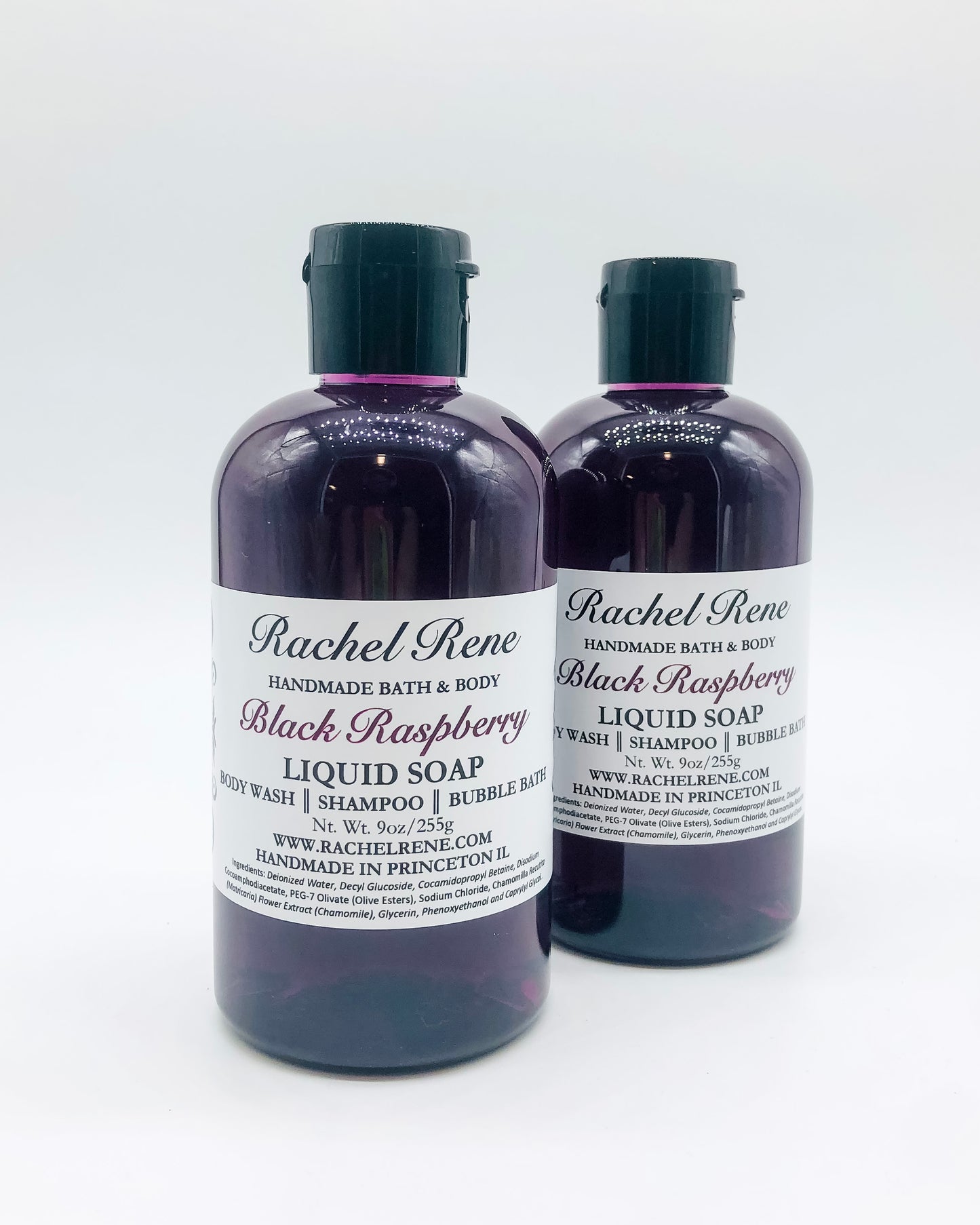 Two purple liquid soaps with white labels that read "Rachel Rene: Handmade Bath & Body - Black Raspberry. Liquid Soap - Body Wash - Shampoo - Bubble Bath." They have black pull top caps all in front of a white background.