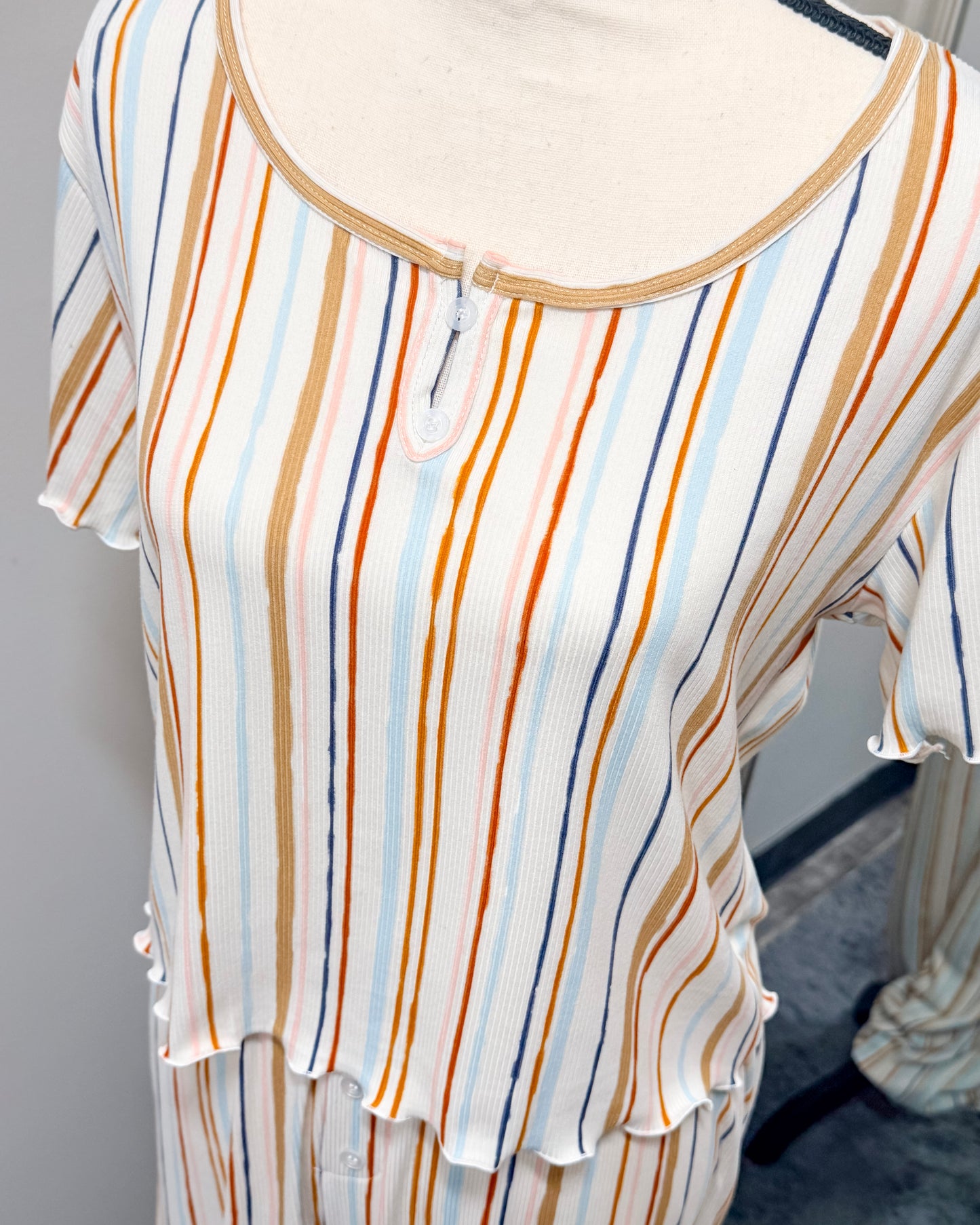 Multi-colored striped pajama top on a mannequin against a gray background
