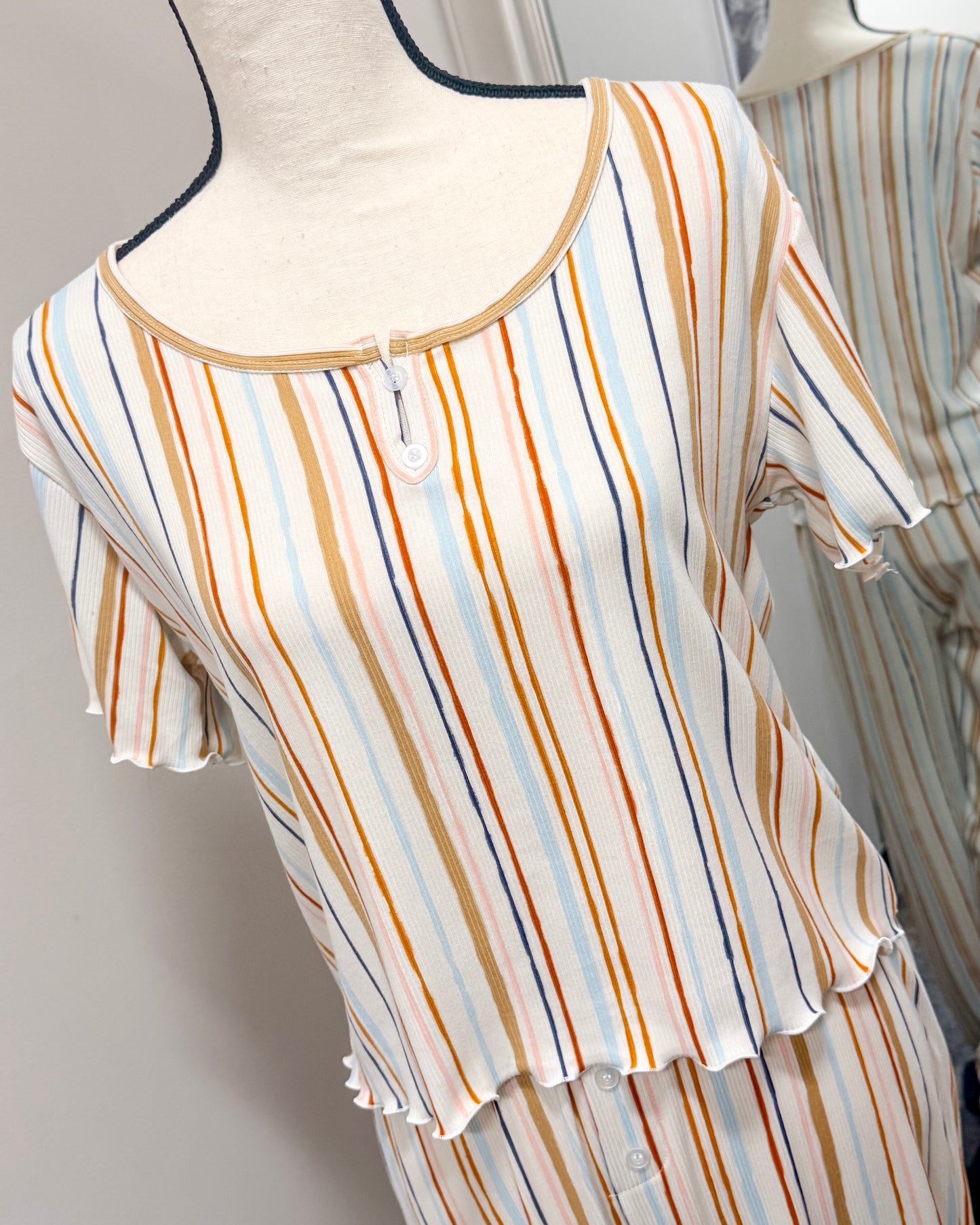 Multi-colored striped pajama set on a mannequin against a neutral background 