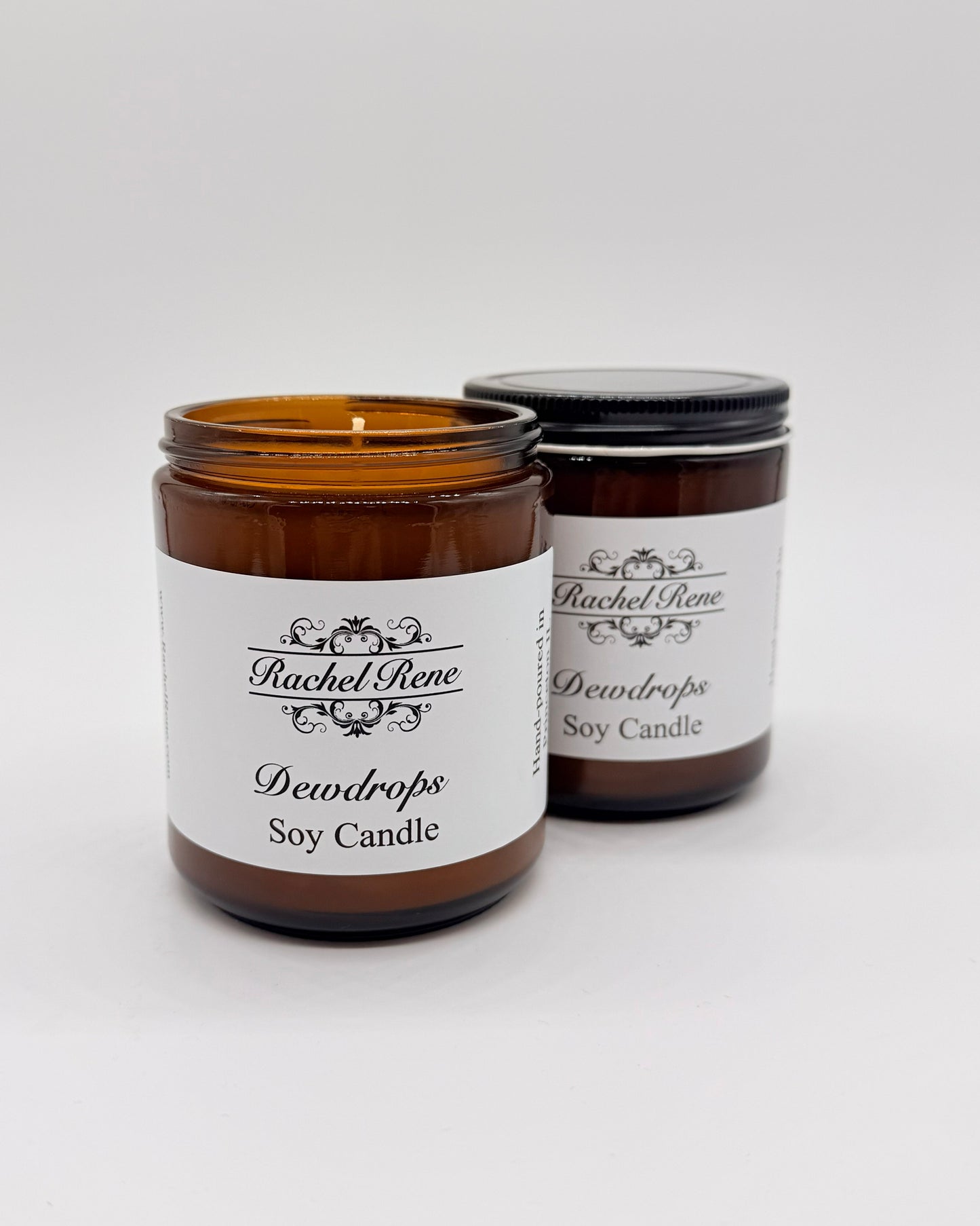 Two Dewdrops soy candles in amber jars with labels on a white background