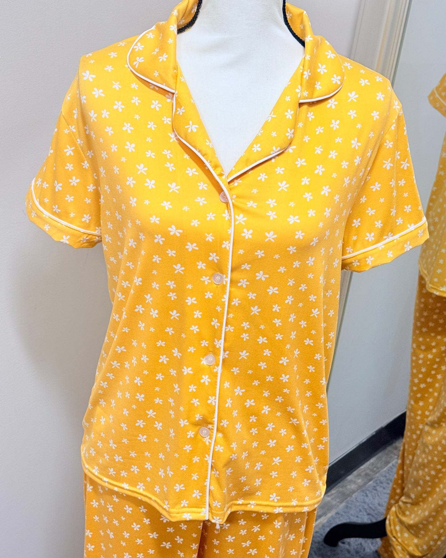 Yellow pajama set with white floral pattern on a mannequin against a plain background