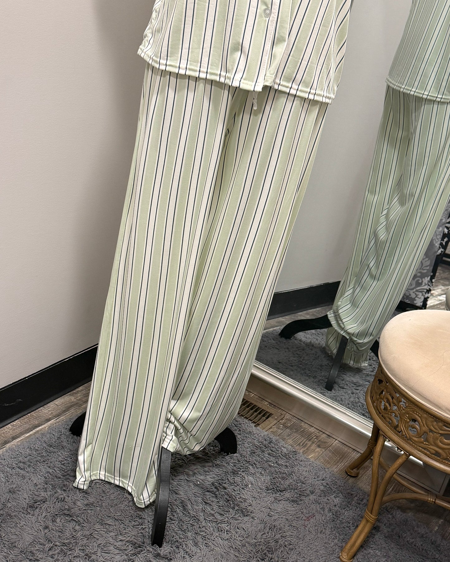 Green and white striped pajama set on a mannequin against a neutral wall.