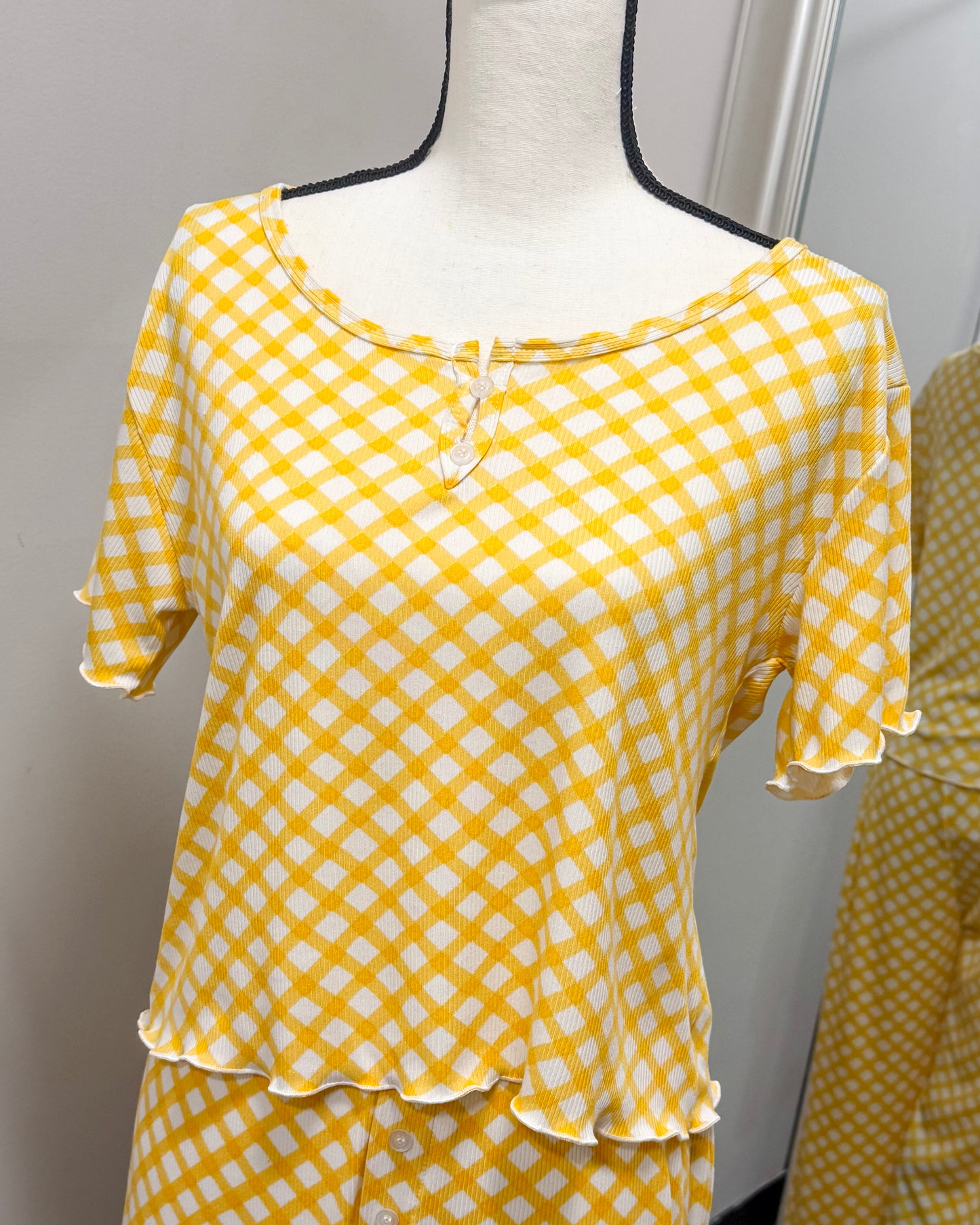 Yellow and white checkered pajama top on a mannequin against a neutral background