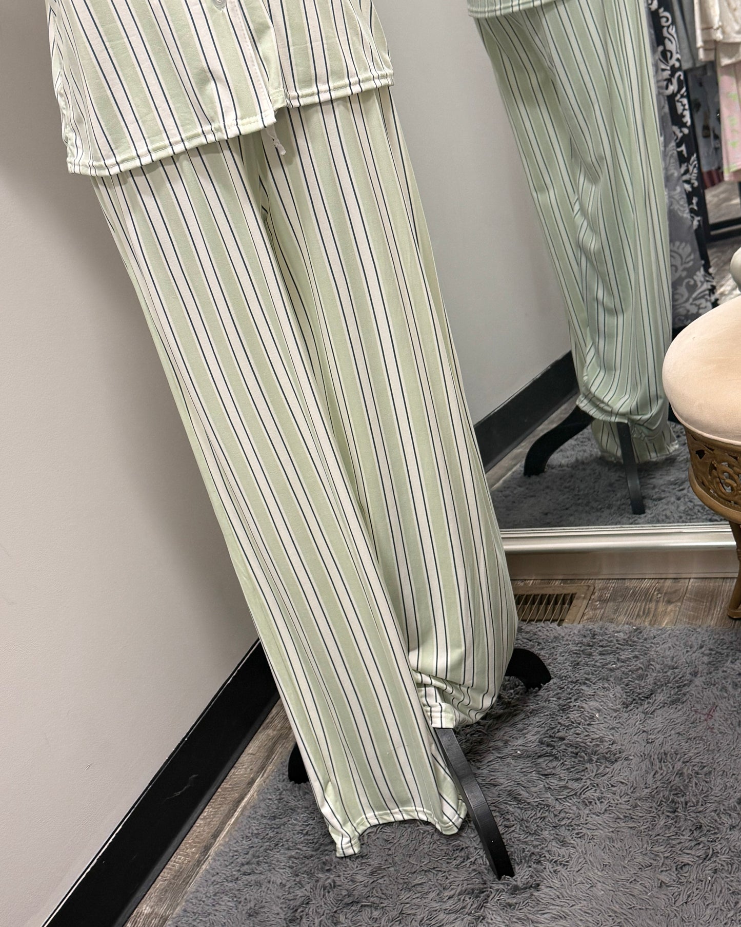 Green and white striped pajama set on a mannequin against a mirror.