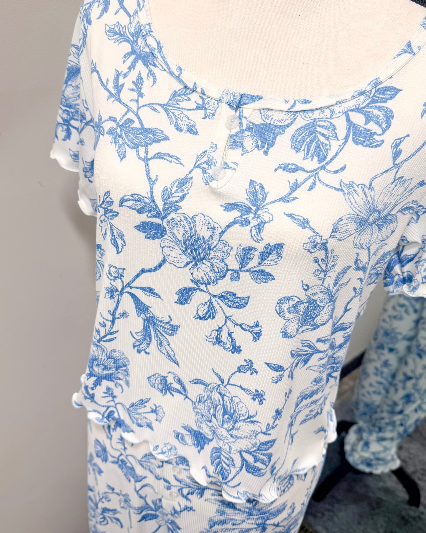 White pajama top with scoop neck and blue floral pattern again a gray background