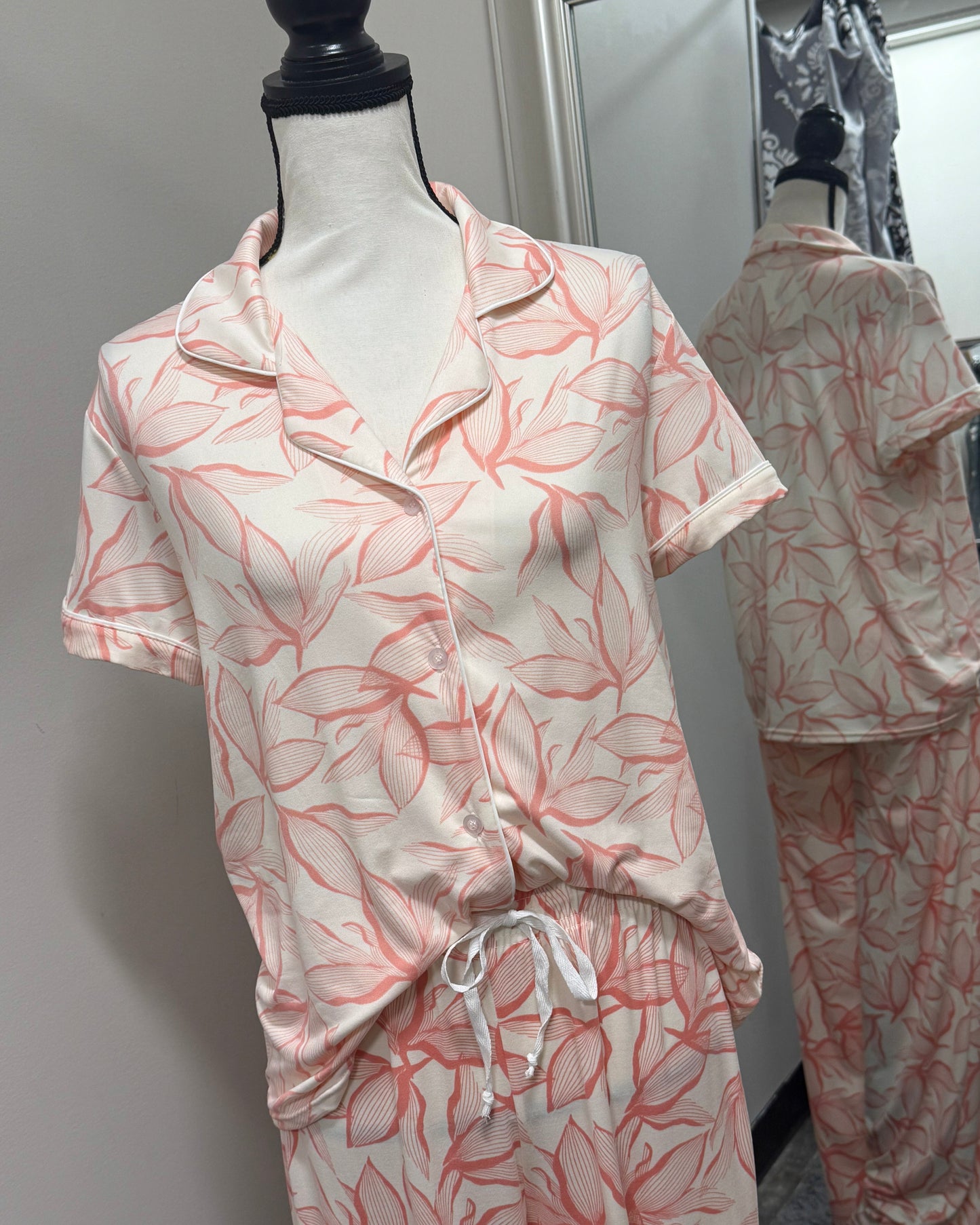 Pink and white pajama set on a mannequin against a plain background