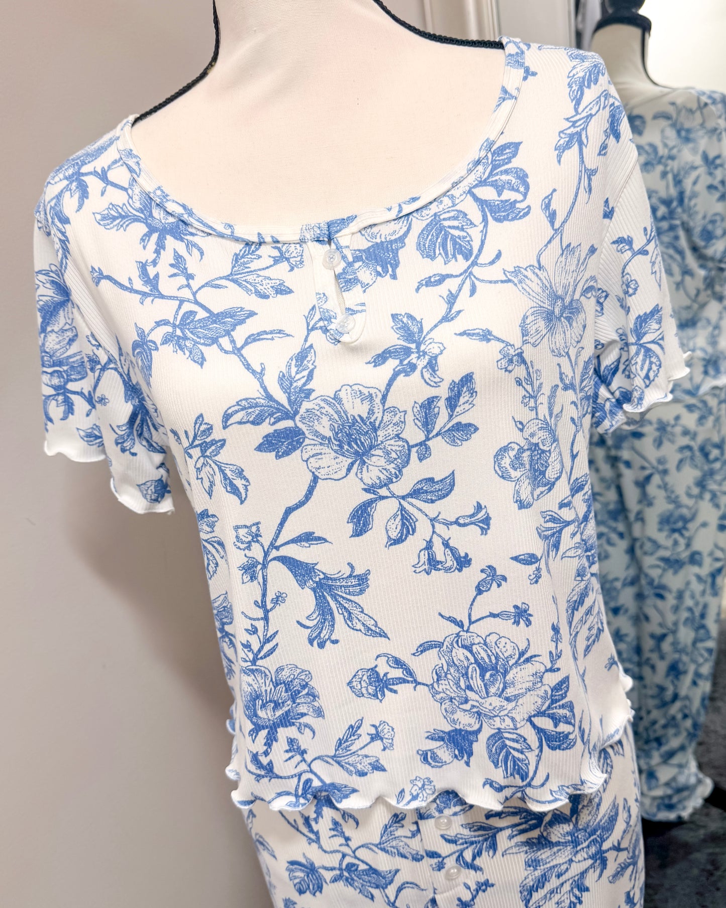 White pajama top with blue floral pattern on a mannequin against a neutral background