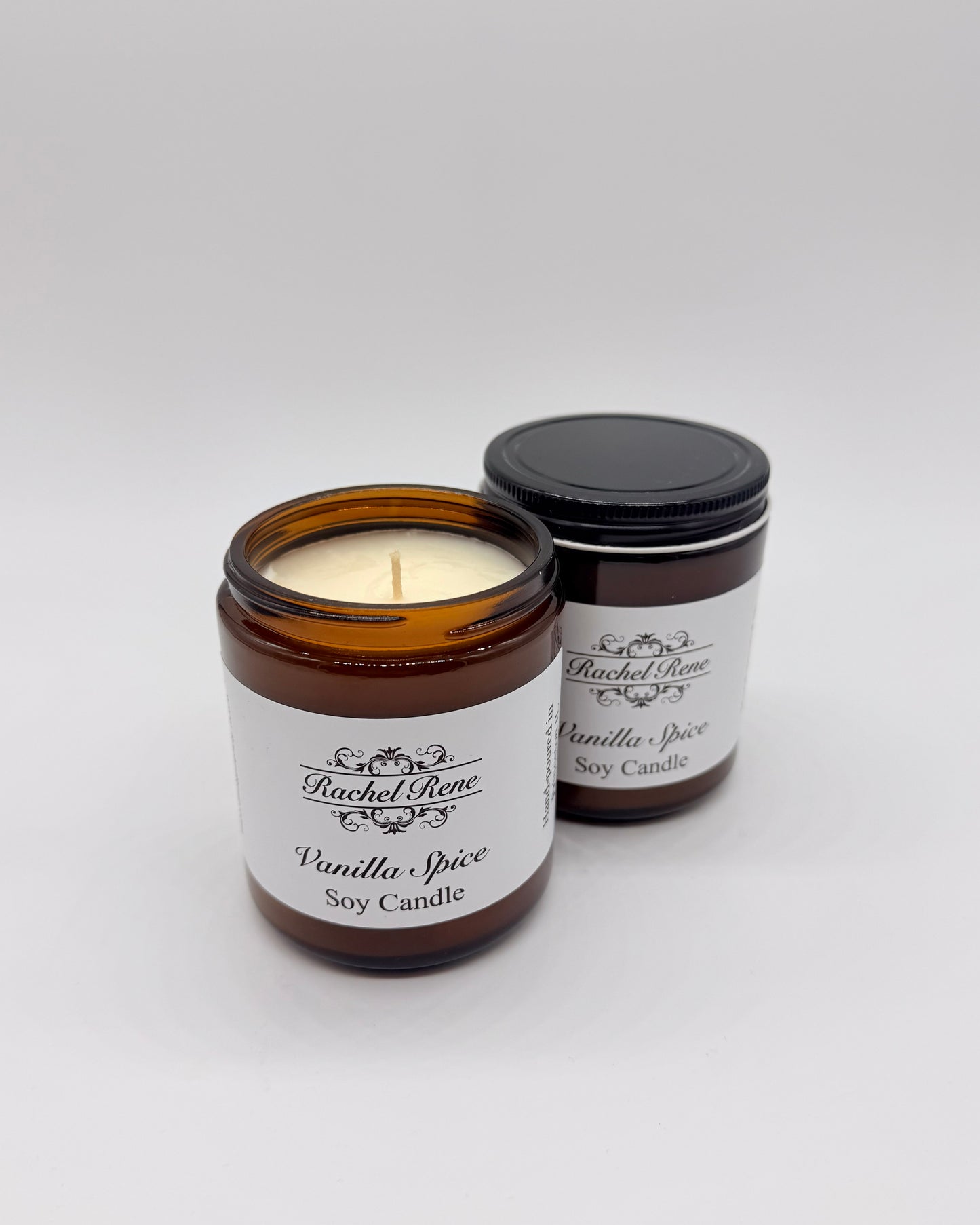 Two candles in amber jars labeled 'Vanilla Spice' by Rachel Rene on a white background