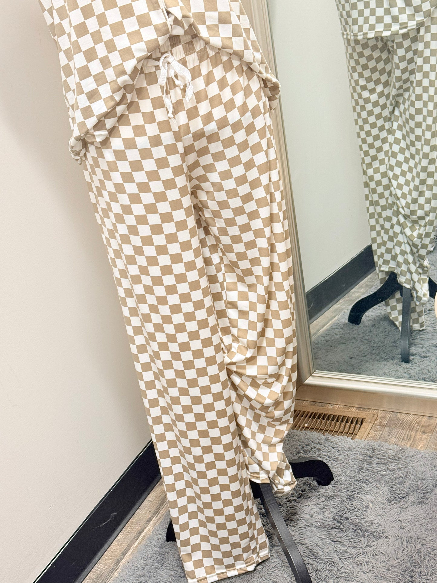 Beige and white checkered pajama pants on a mannequin in front of a mirror.