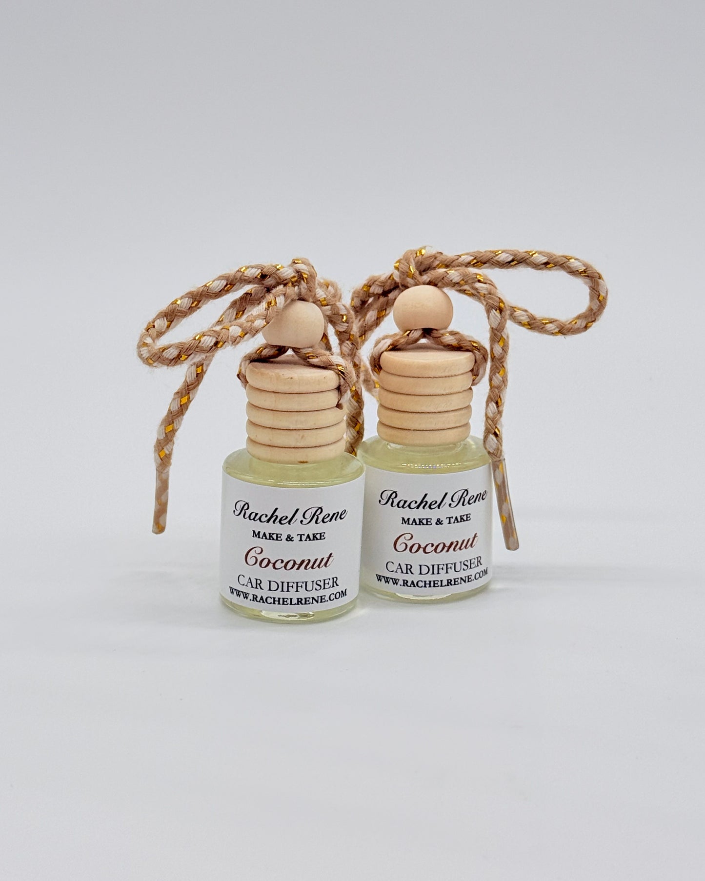 Two bottles of Rachel Rene Car Diffuser with wooden tops and braided string on a white background