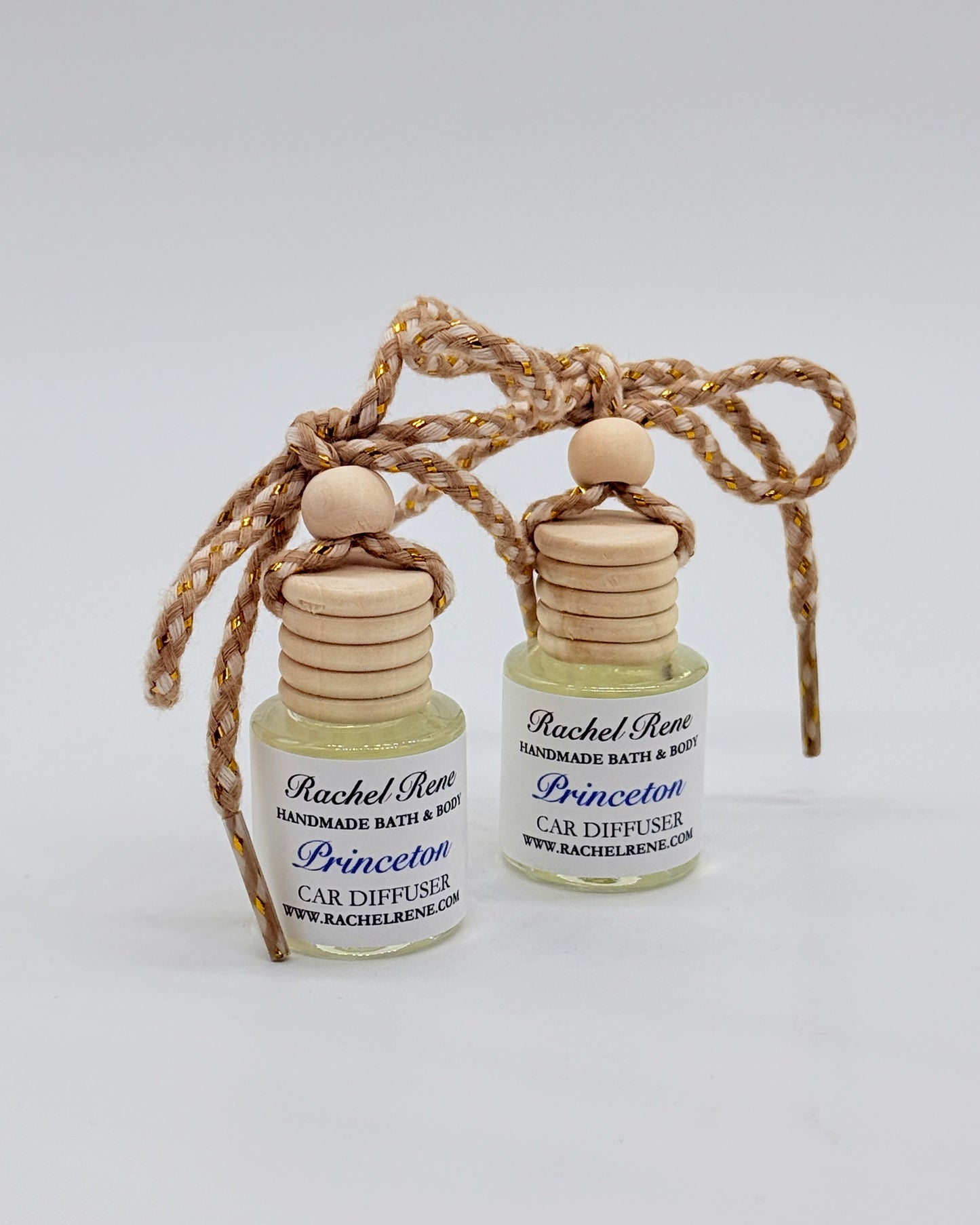 Two bottles of Rachel Rene Car Diffuser with wooden tops and braided string on a white background