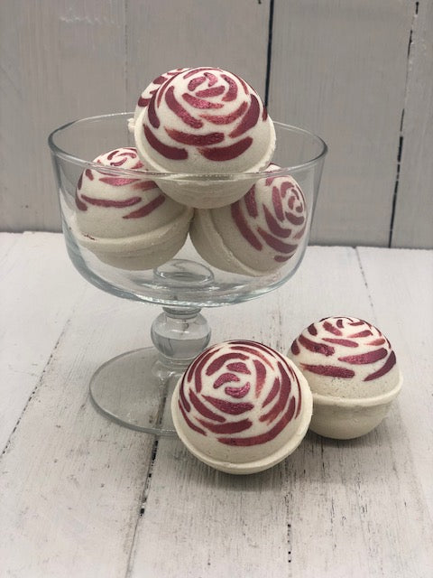 Rose scented round bath bombs in a white color painted on the top in red like the top like rose petals