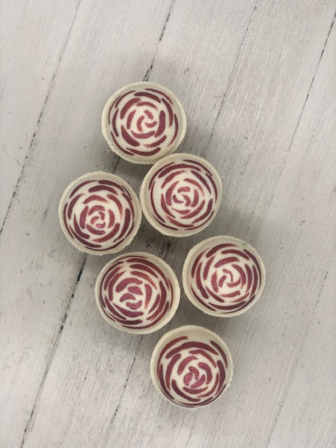 Rose scented round bath bombs in a white color painted on the top in red like the top like rose petals