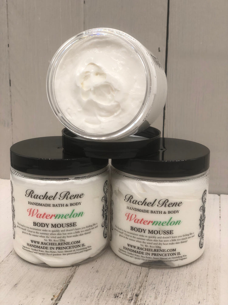 Watermelon scented body mousse that is white in color in a clear jar with a black lid 