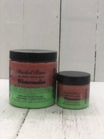 Watermelon scented body polish sugar scrub in a clear jar with a black lid the body polish is colored green on the bottom and red on the top half