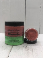 Watermelon scented body polish sugar scrub in a clear jar with a black lid the body polish is colored green on the bottom and red on the top half