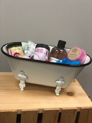 A large white decorative bathtub to hold products with detailed footing and black trim on the top.