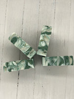 A white bar of soap with dark green swirls.