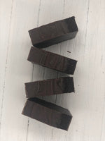 A dark brown soap bar with coffee grounds pressed into the top of the soap.