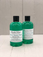 A clear bottle with teal liquid soap inside. A white label reads "Aloe & Summer Herbs".
