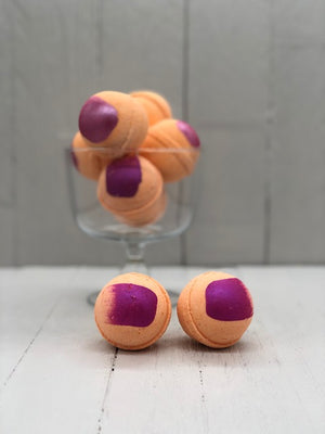 Orange bath bombs with a pink paint streak.