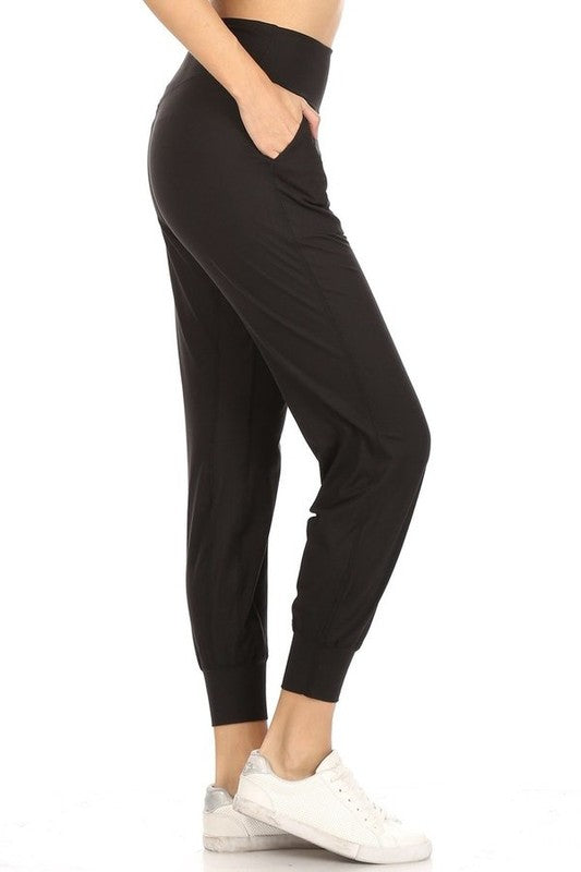 A side view of black joggers. The bottoms are cinched to just above the ankle. The model puts her hand in the side pocket.