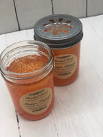 Orange jelly crystals in a clear glass jar. The lid has holes in a flower design. A tan label reads "Mango Papaya"
